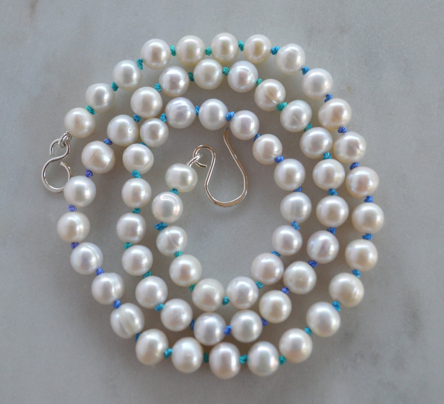 Luminescent 7-8mm Pearls Hand Knotted on Teal and Purple Silk Thread. Hand Forged Sterling Silver Hook and Eye Clasp. 20"