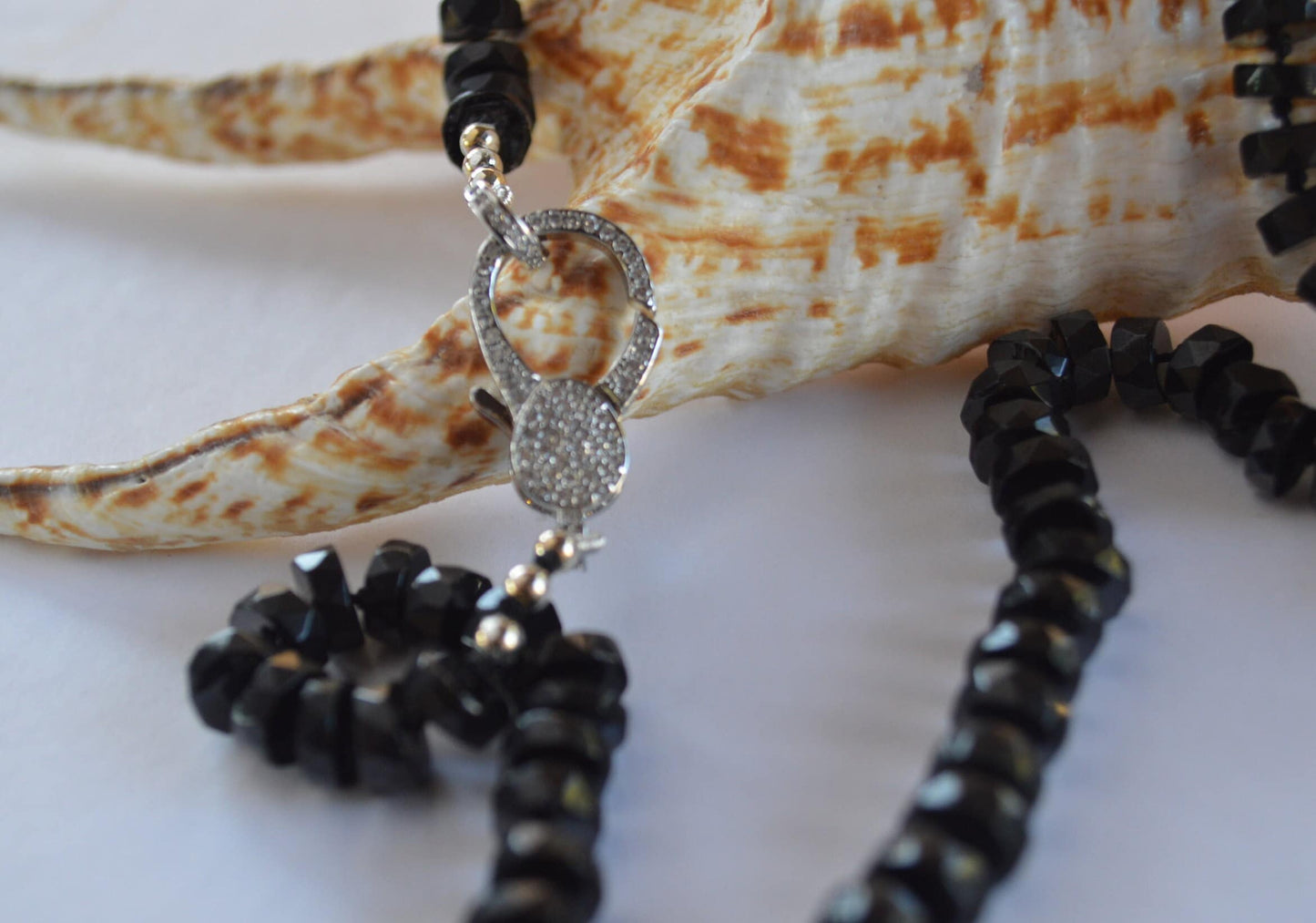 Black Spinel 7mm Faceted Heishi Beads Hand Knotted on Black Silk. Sparkly CZ Lobster Clasp Can Be Worn In Front With Charms, or In Back. 22"