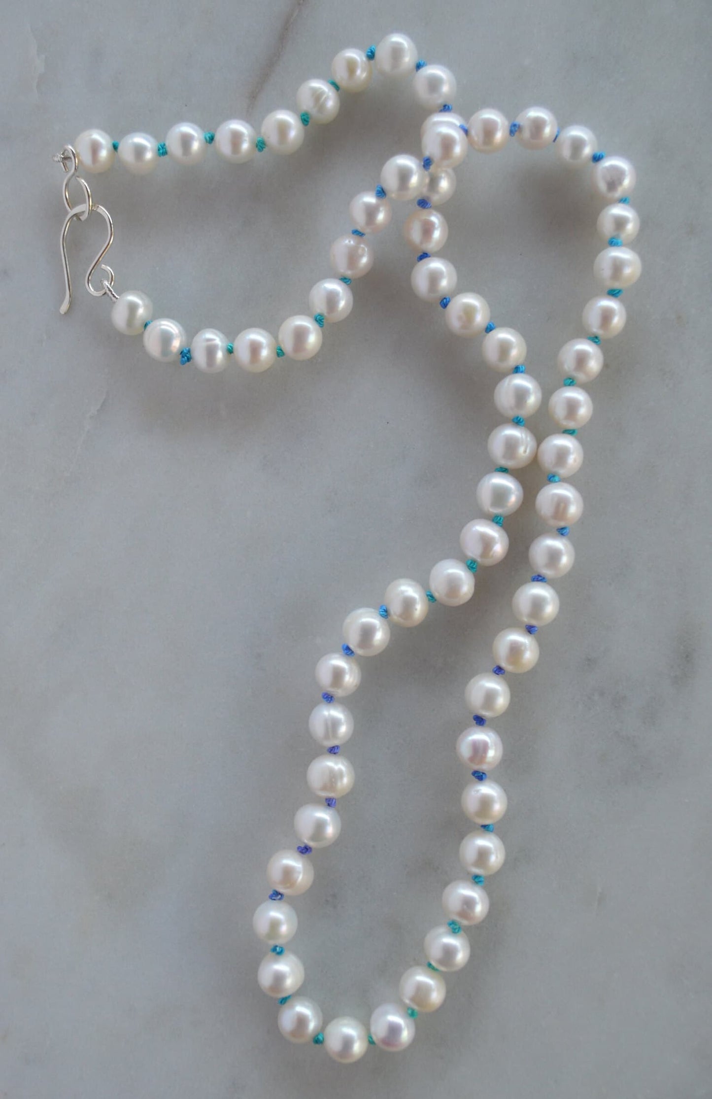Luminescent 7-8mm Pearls Hand Knotted on Teal and Purple Silk Thread.  Hand Forged Sterling Silver Hook and Eye Clasp. 20"