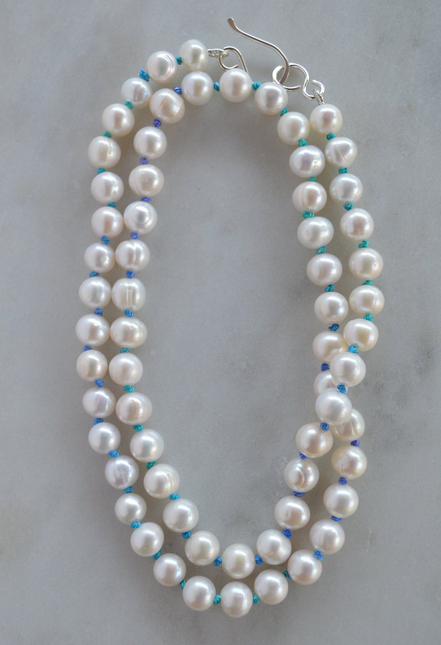 Luminescent 7-8mm Pearls Hand Knotted on Teal and Purple Silk Thread.  Hand Forged Sterling Silver Hook and Eye Clasp. 20"