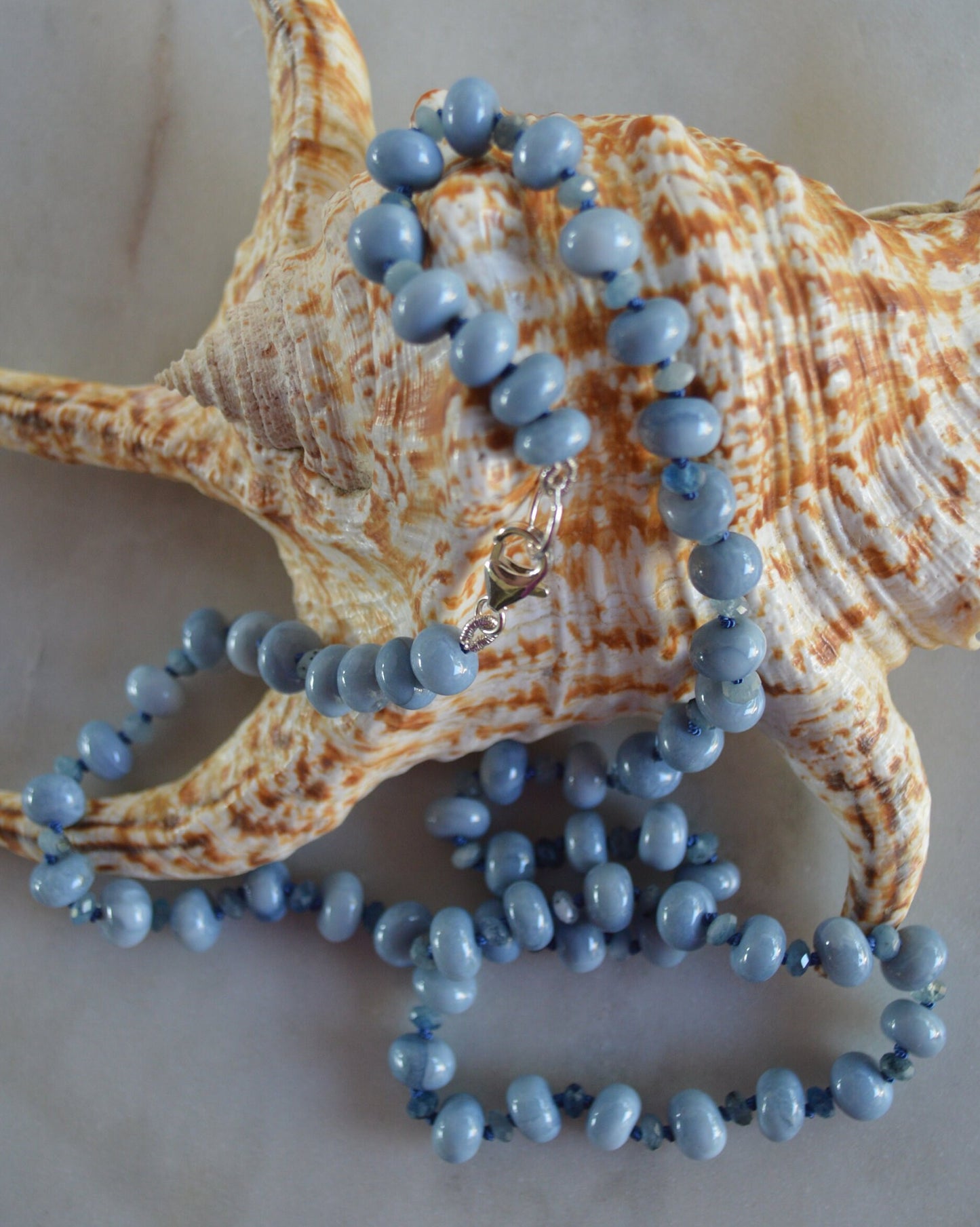 Sky Blue Smooth Opal Rondelles and Stormy Blue Aquamarine Gemstones Hand knotted on Blue Silk.  Sterling Lobster Clasp. 22"