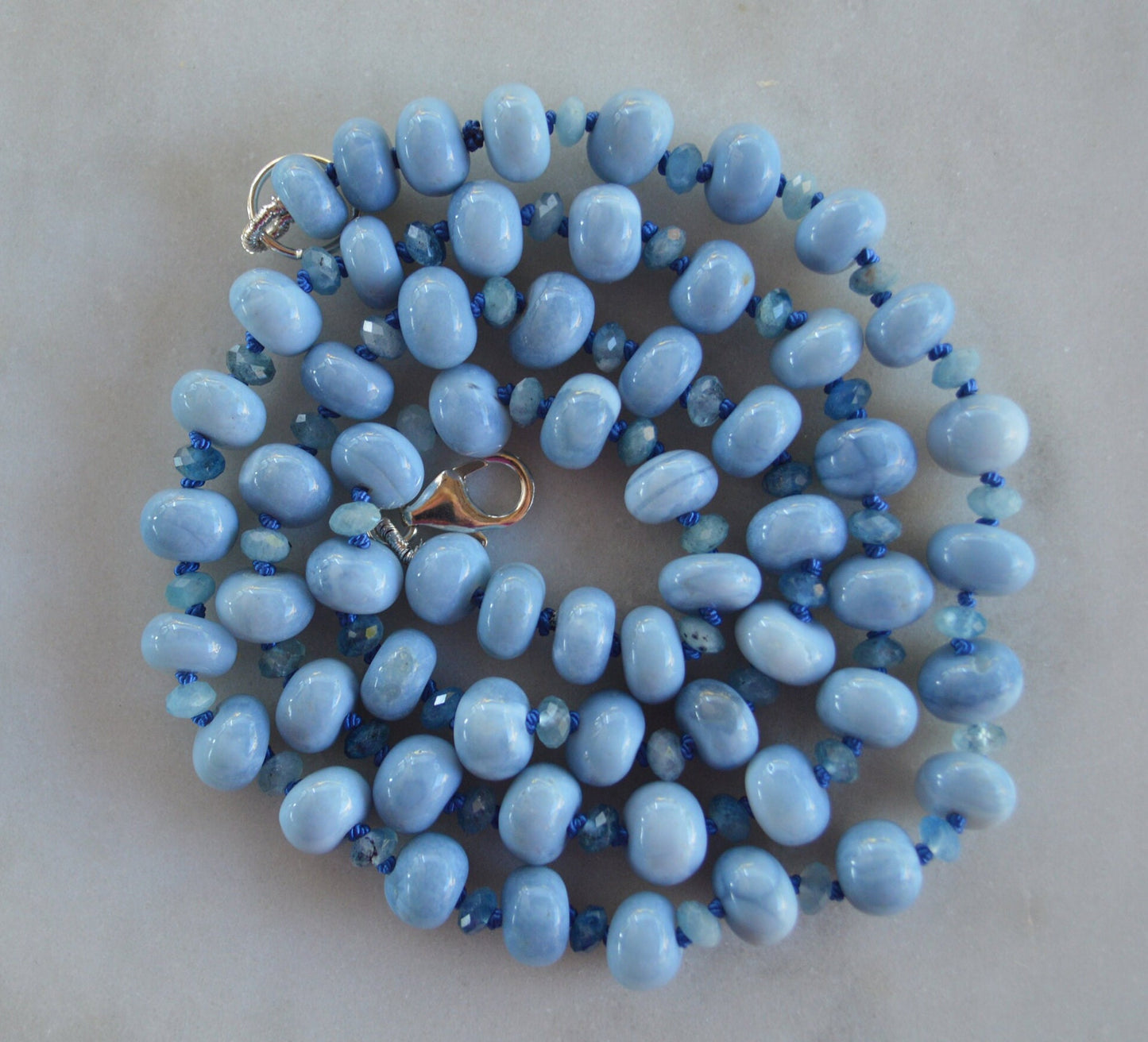 Sky Blue Smooth Opal Rondelles and Stormy Blue Aquamarine Gemstones Hand knotted on Blue Silk.  Sterling Lobster Clasp. 22"