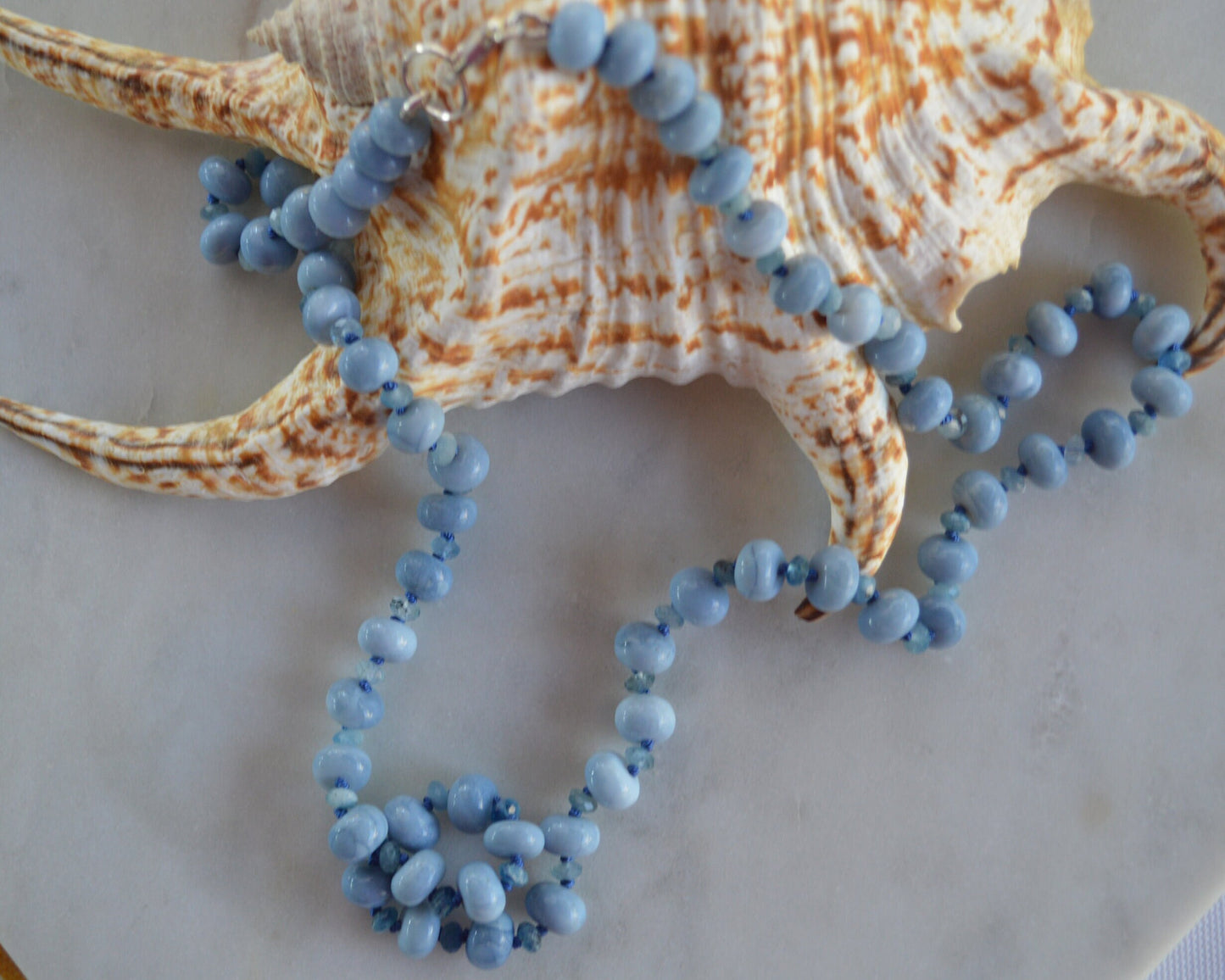 Sky Blue Smooth Opal Rondelles and Stormy Blue Aquamarine Gemstones Hand knotted on Blue Silk.  Sterling Lobster Clasp. 22"
