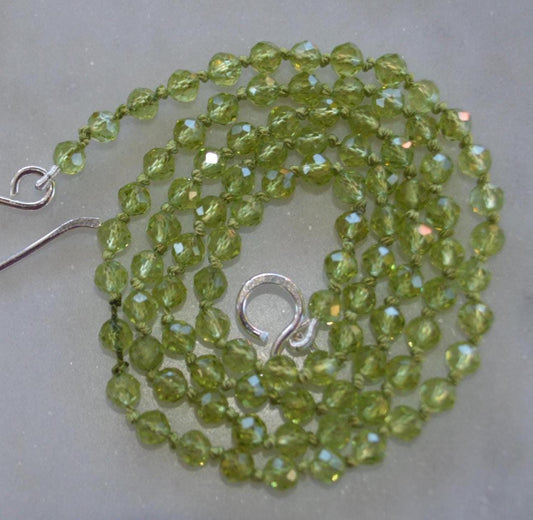 Sparkly Faceted Round Peridot Gemstones Hand Knotted on Green Silk.  Finished with Sterling Silver Hook And Eye Clasp 22" Long. 4mm Stones