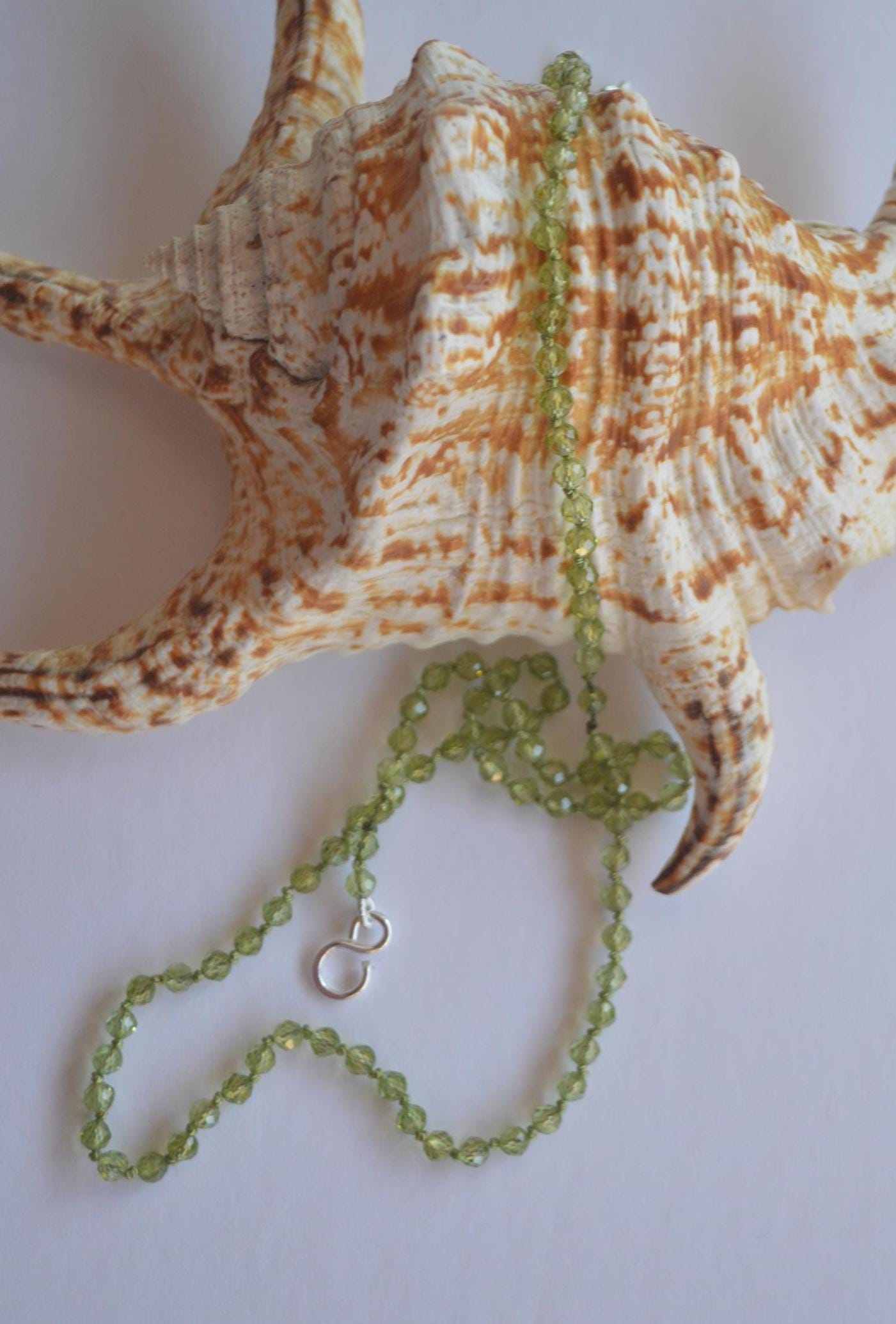 Sparkly Faceted Round Peridot Gemstones Hand Knotted on Green Silk.  Finished with Sterling Silver Hook And Eye Clasp 22" Long. 4mm Stones