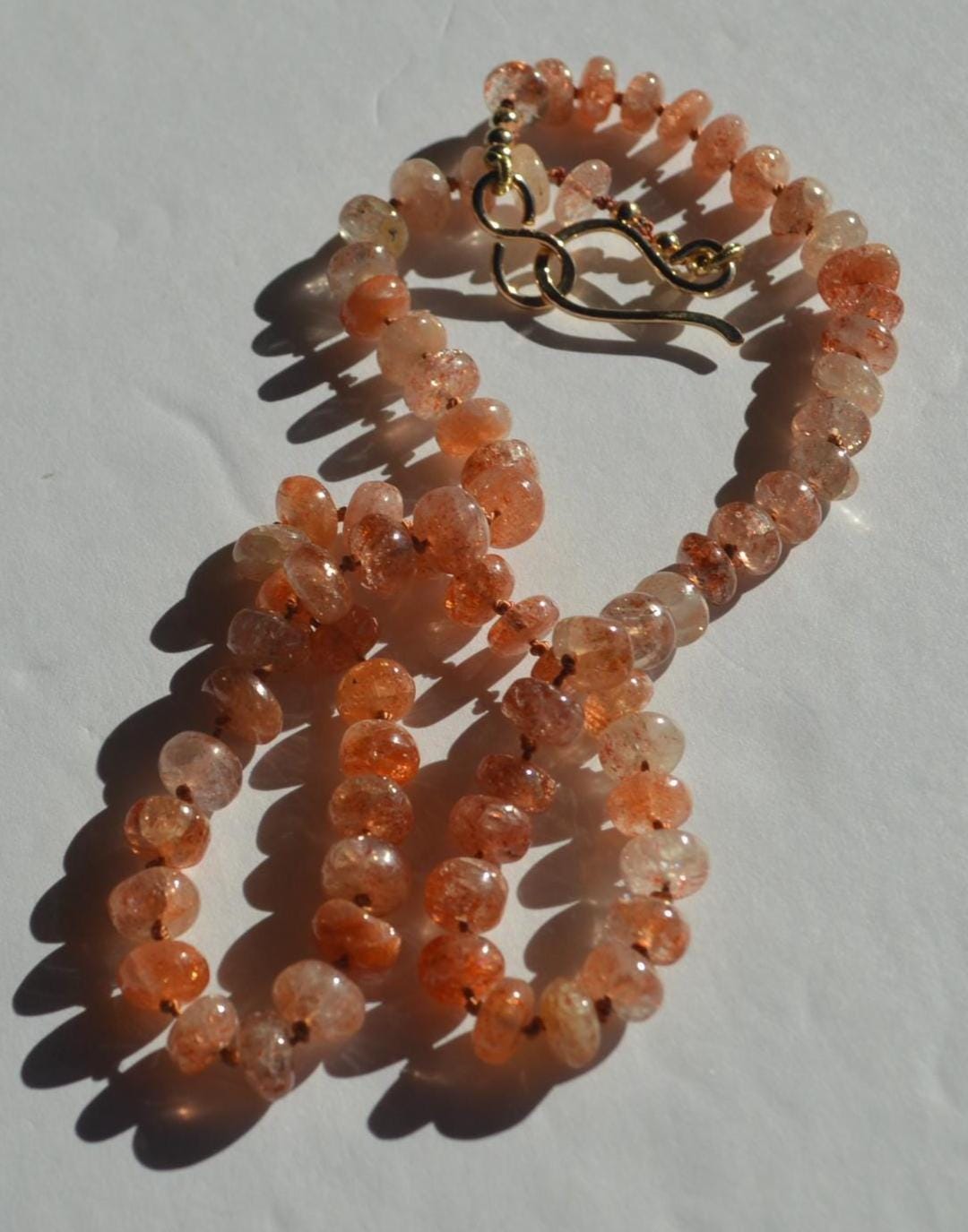 Natural 7mm Sunstone Gemstones Hand Knotted on Coral Silk.  This Piece is Finished with a Hand Forged GF Hook & Eye Clasp. 18.5" Long.